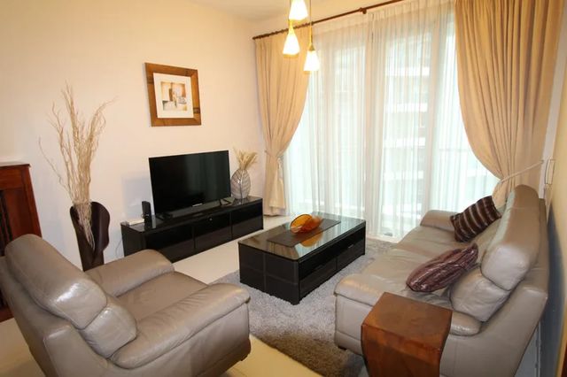 Living room with leather sofas, television and full-height windows